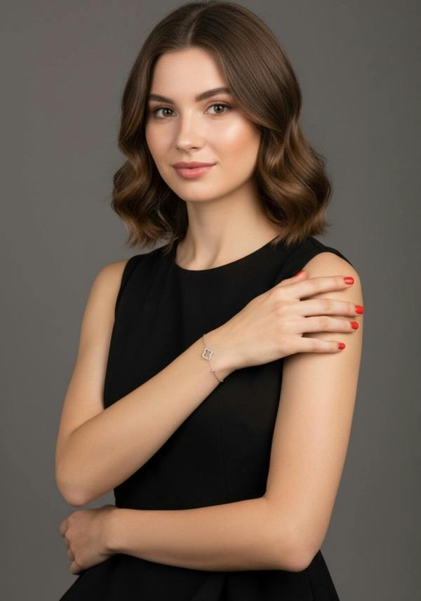 Woman in a black dress against a gray background wearing a silver clover bracelet