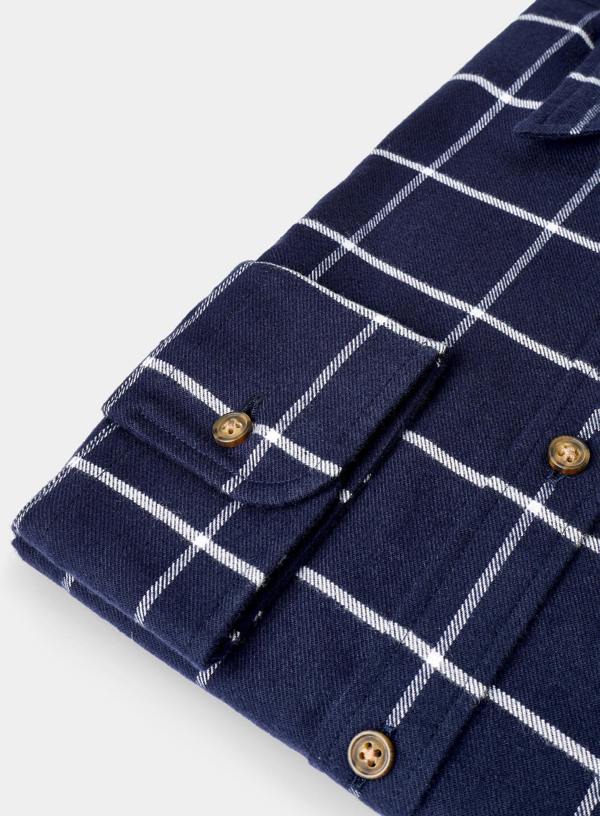 Close-up of a navy blue shirt with white check pattern and gold buttons on a light gray background