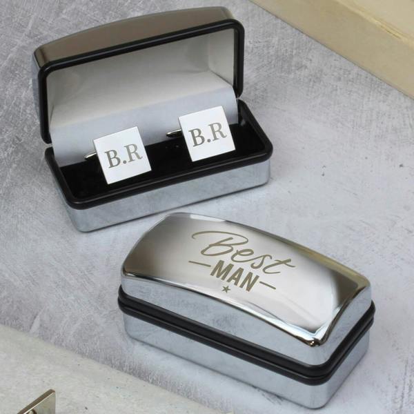 A pair of personalised silver square cufflinks engraved with the initials 'O.R.' resting inside an open chrome presentation box engraved with 'Best Man' on the lid against a dark background.