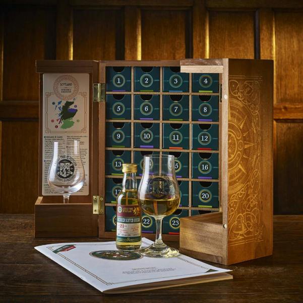 Opened handmade wooden whisky advent calendar cabinet filled with 24 numbered drawers, a tasting glass, a miniature Blended Scotch Whisky bottle, and tasting notes booklet.