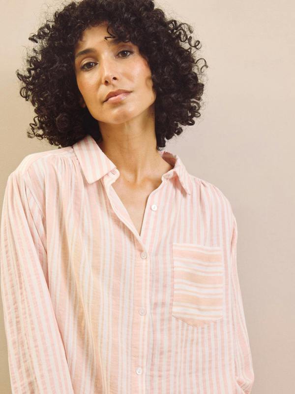 Woman wearing a pink striped pyjama shirt against a neutral background