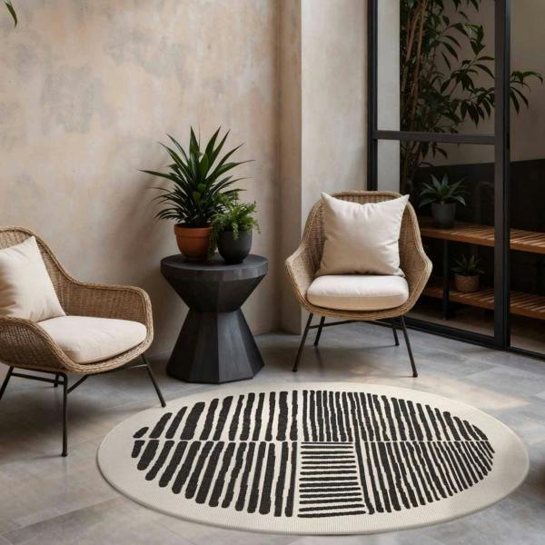 Round black and white patterned rug in a living room with wicker chairs and plants.