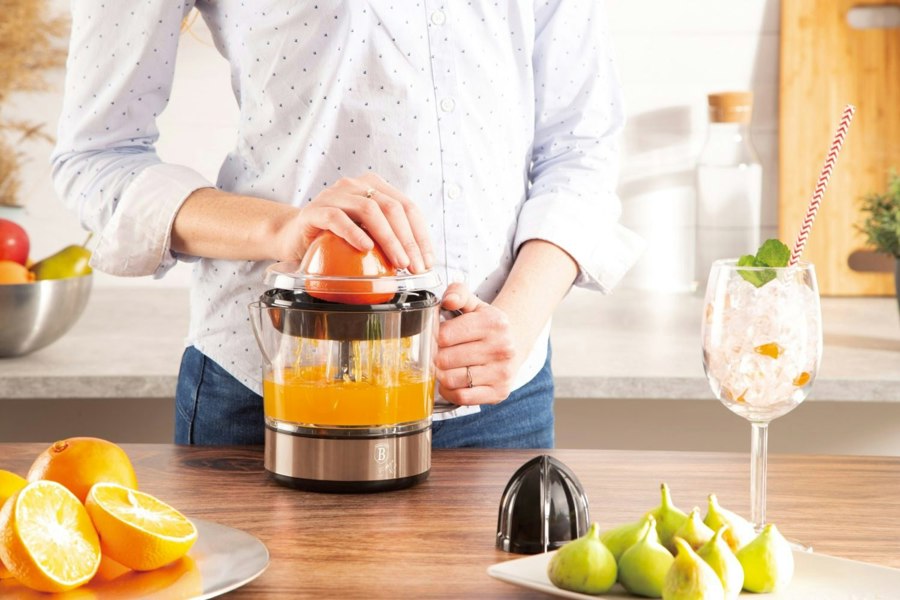 Woman using the Berlinger Haus BH/9385 Electric Citrus Juicer to extract fresh juice from oranges.