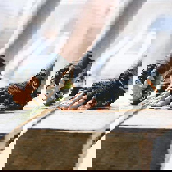 Scruffs Trade Fingerless Mens Work Padded Palm Gloves, close-up of a person measuring wood with a measuring tape wearing black padded palm gloves.