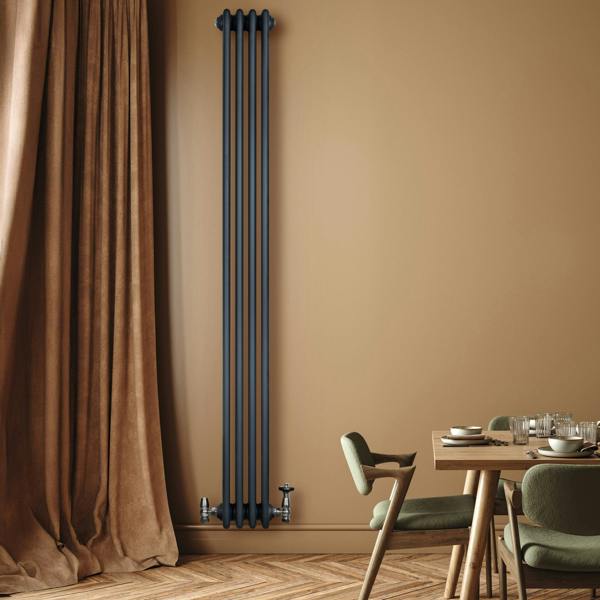 Traditional anthracite grey 4 column radiator with valves, mounted on a warm-toned wall, complementing a stylish dining area