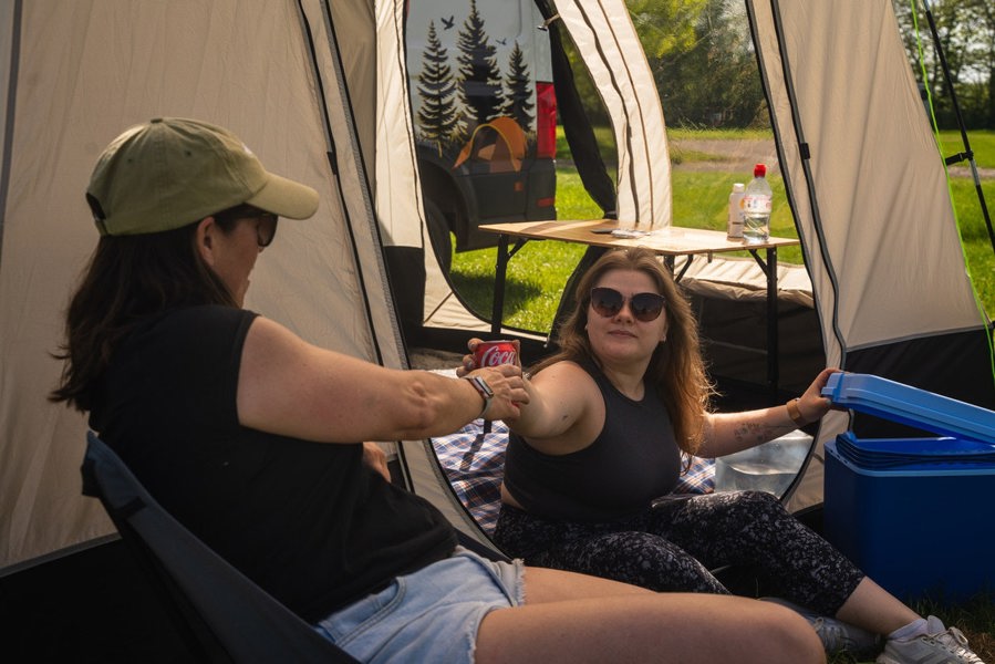 A couple of people relaxing outside of the Cubo XL Motorhome Awning - Fibreglass Poles that is attached to a VW Van.