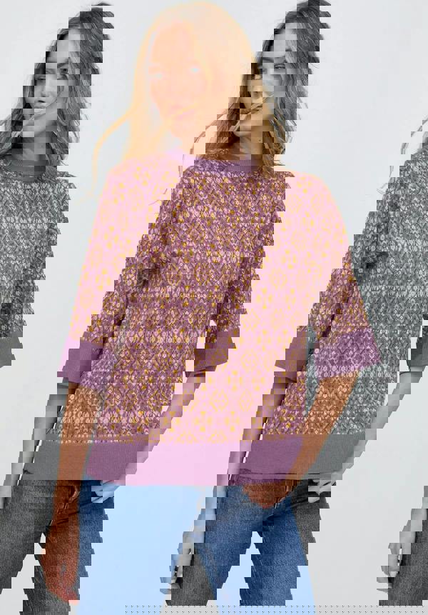 Woman wearing a patterned purple sweater and blue jeans on a white background
