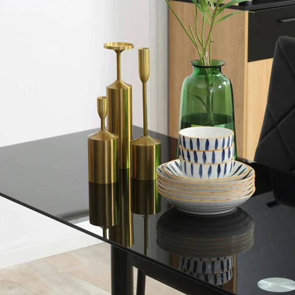 Black glass dining table with decorative candle holders and chair back