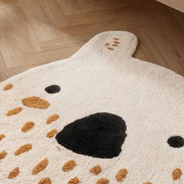 Dog-shaped rug with brown spots on a wooden floor