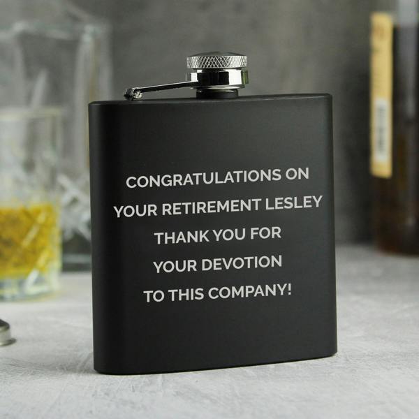 Personalised matte black retirement hip flask with silver engraving that reads congratulations on your retirement Lesley thank you for your devotion to this company.