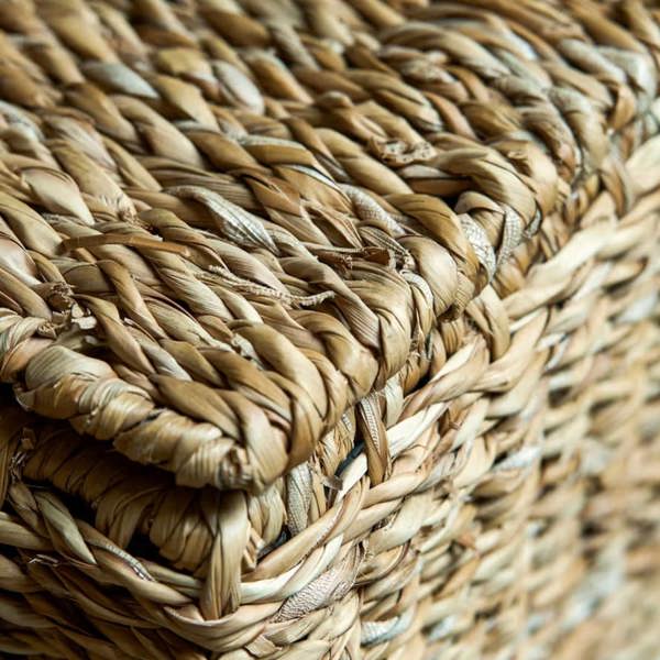 Close-up view of the intricate handwoven natural seagrass texture and corner craftsmanship on the laundry basket.