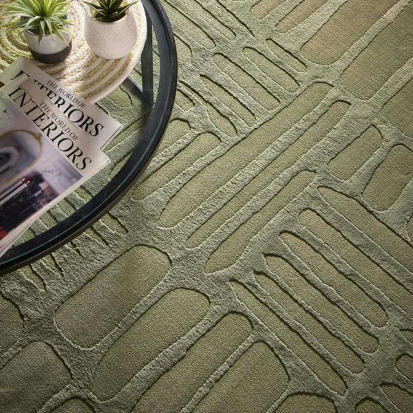 Textured green carpet with a pattern, a glass table, and a magazine on top.