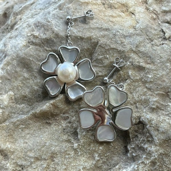 Silver floral earrings with pearl and mother of pearl on a rock.