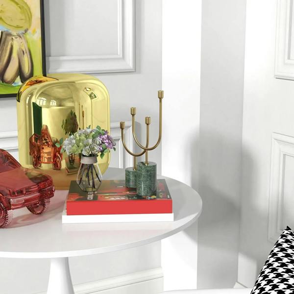White round dining table with pedestal base shown from side with decor on tabletop
