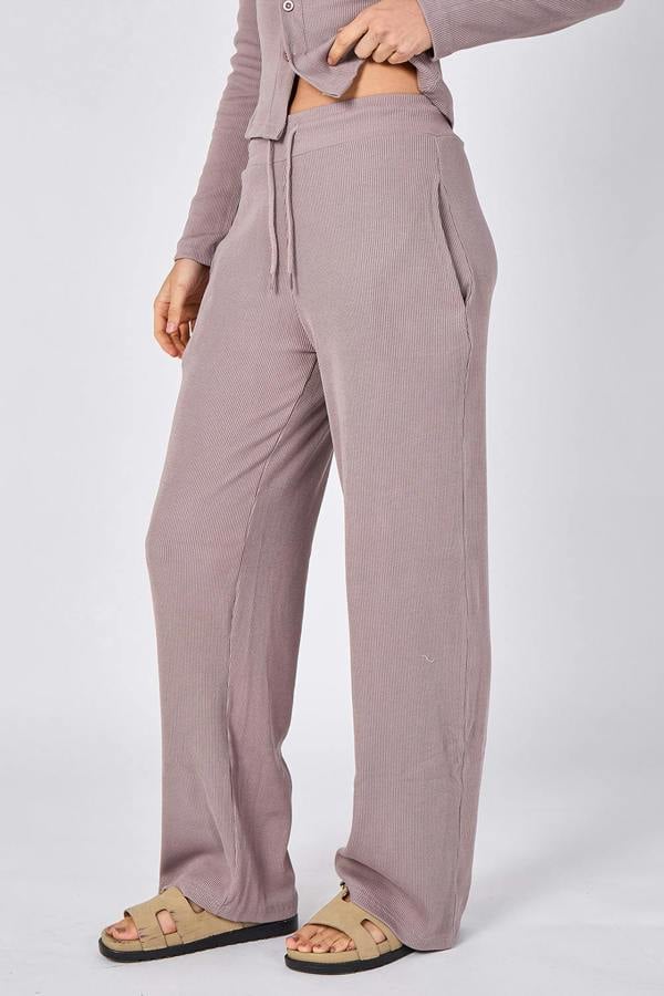 Person wearing mauve lounge pants and cardigan on a white background