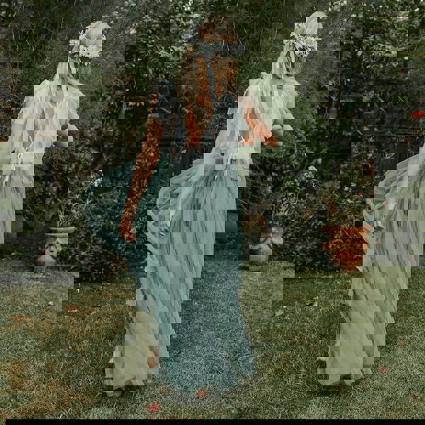 Girl in a garden twirling wearing a Bohemian Serendipity Dress in sage green