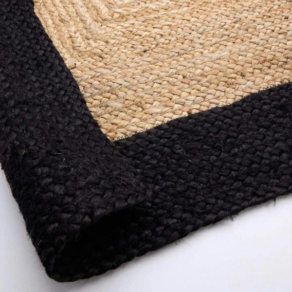 Close-up of a black and beige woven rug corner on a white background