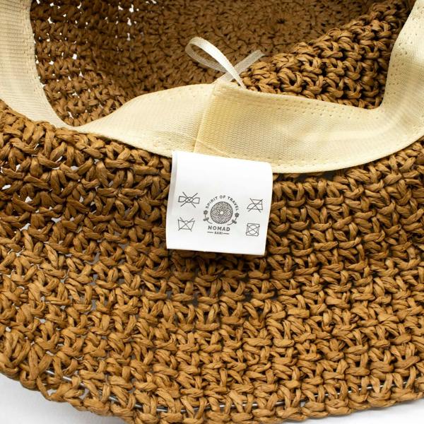 Natural tan straw floppy sun hat with cream ribbon tie and brand tag