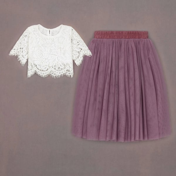 White lace top and purple pleated skirt on a gray background
