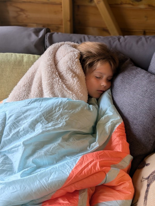 child having a sleep wrapped in the cosy sherpa fleece lined Tonal Tree tops Blanko, enjoying a cosy day on the sofa. imageset:Tonal Tree Tops