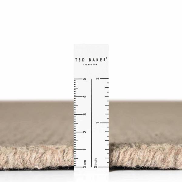 Close-up of a carpet sample with a ruler and 'Ted Baker London' branding.