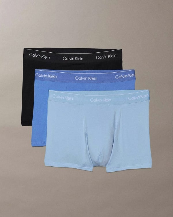 Three pairs of Calvin Klein trunks in black, blue, and light blue.