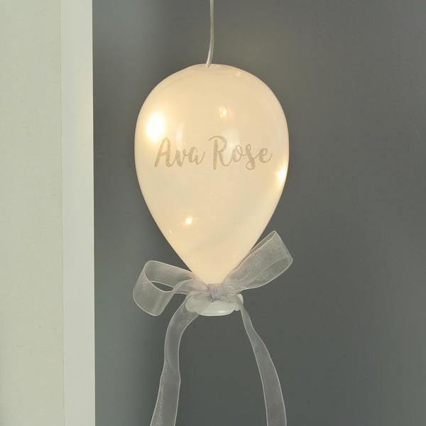 An illuminated frosted white glass balloon decoration with a grey ribbon and the double-barrelled name Ava Rose.
