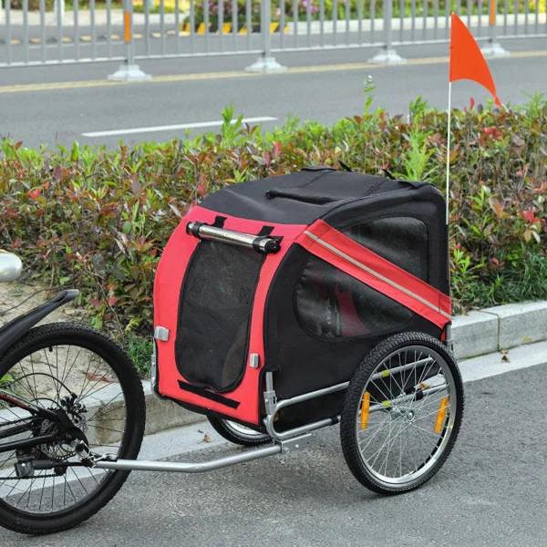 Red and black bicycle pet trailer with orange flag, mesh windows, and spoked wheel