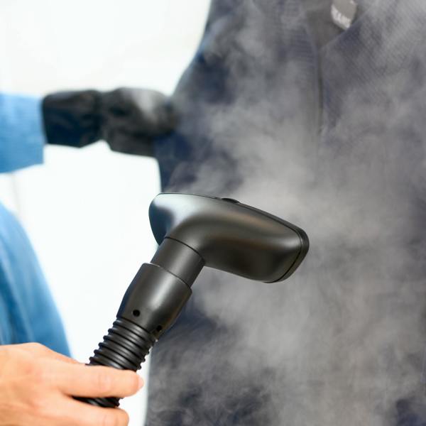 A person uses the Fridja f1600 Commercial Clothes Steamer to remove wrinkles from a dark garment, with steam rising for expert garment care.