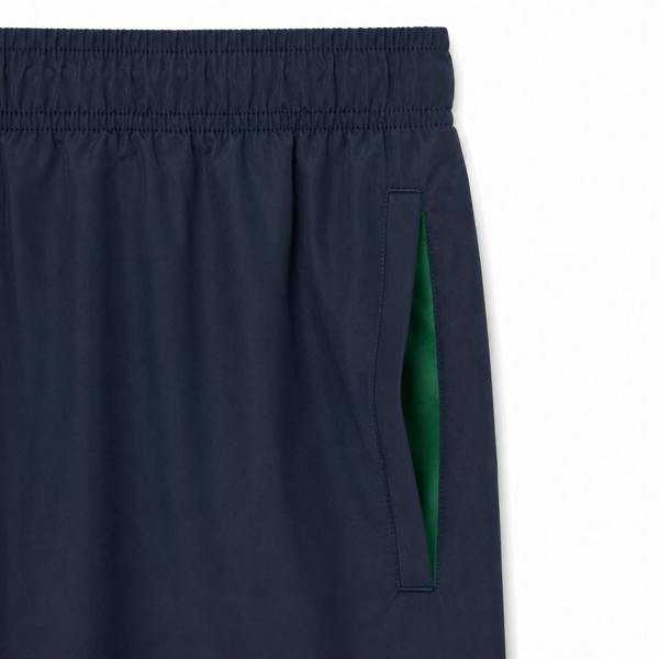 Lacoste navy blue quick-dry swim shorts with elastic waistband and green pocket lining.