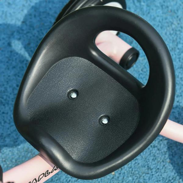 Black steering handle of a pink kids tricycle, close-up