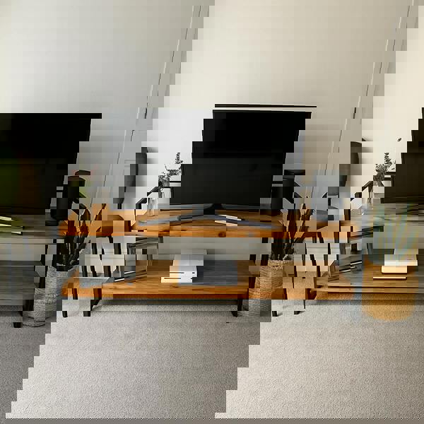 Wooden TV stand with a television, speakers, and decorative items in a room.