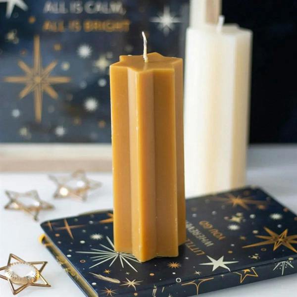 Gold taper candle with star-shaped top, lit