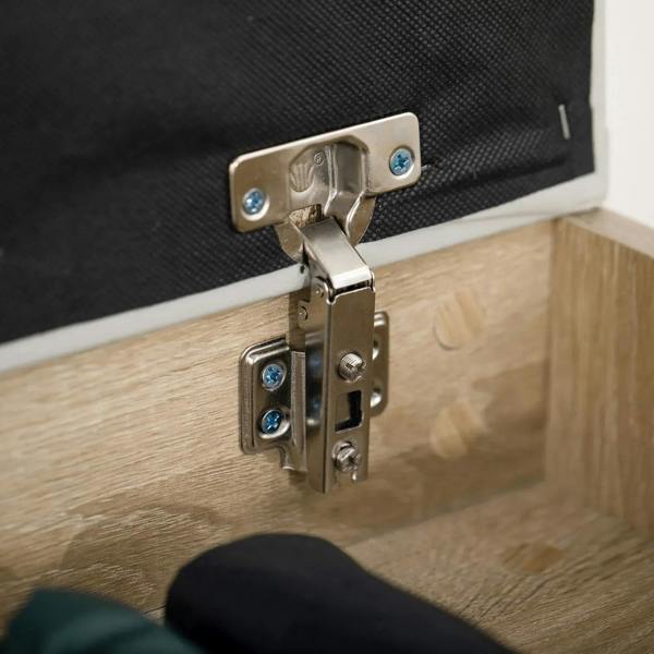 Metal hinge latch on black interior lid of oak-tone shoe cabinet bench with padded seat
