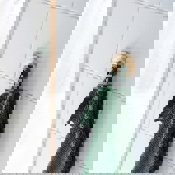 Single brushed brass towel hook on bathroom wall