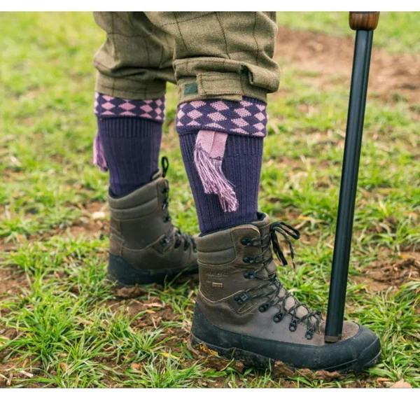Shooter wearing Jack Pyke Hunters boots with patterned shooting socks on grassy field