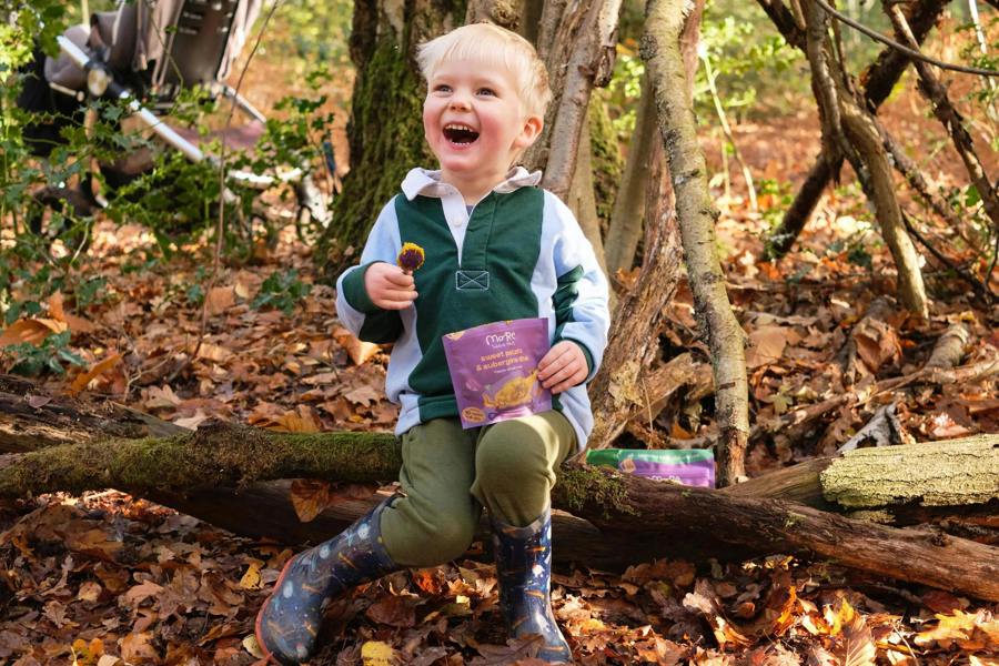 A toddler eating a more toddler meal in a forest. 