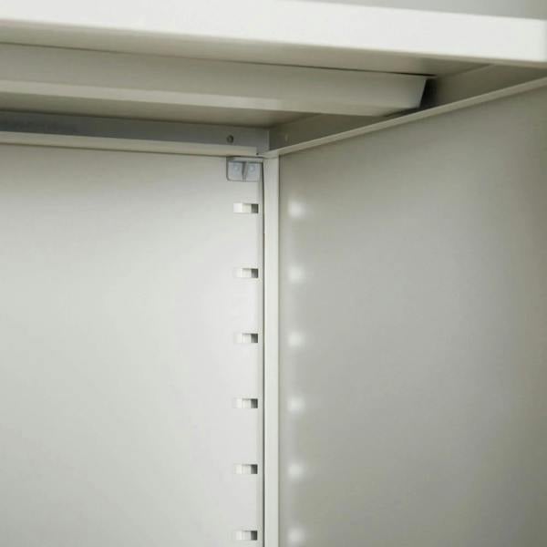White cabinet interior corner with shelf bracket points and adjustable support holes.