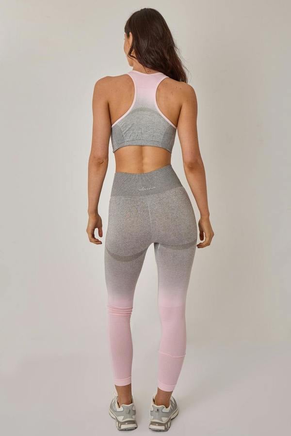 Woman wearing a gray and pink athletic outfit on a plain background