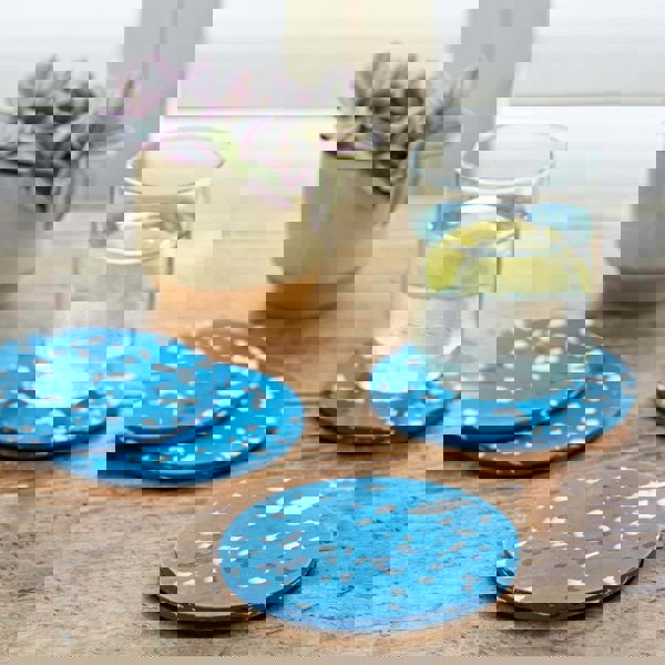 Round plastic coasters with blue splatter designs on a wooden table.