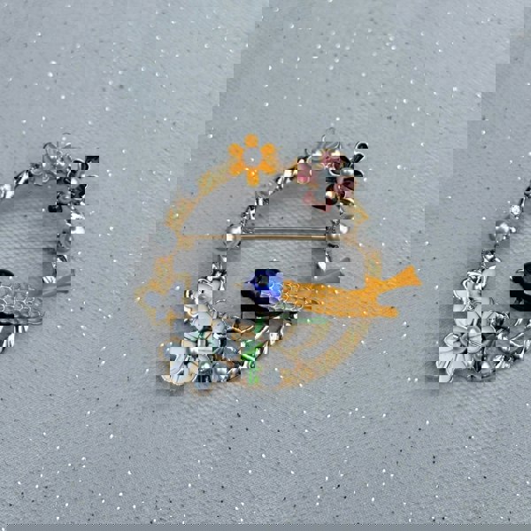 Vintage bird brooch, gold tone setting, multicolour enamel wings and body, perched on decorative floral garland branch, intricate detailing, nature inspired jewellery, elegant statement accessory, timeless gift for her
