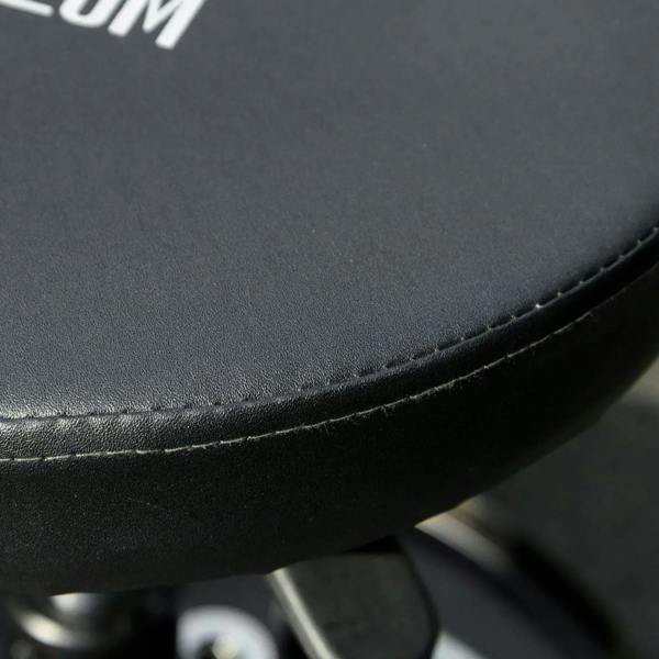Close-up of black padded seat with stitched edge on an adjustable stool