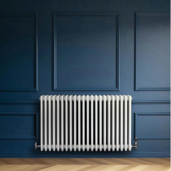 Traditional white 4 column radiator mounted on a blue wall, featuring a sleek design and smooth, glossy finish