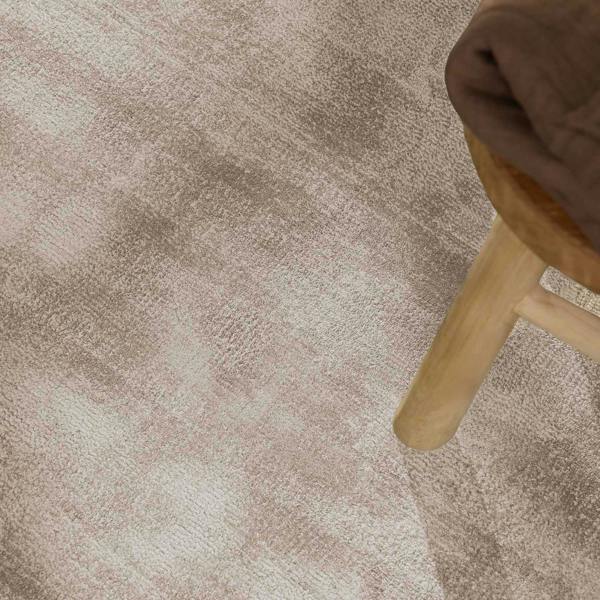 Close-up of a textured beige carpet with a wooden stool corner.