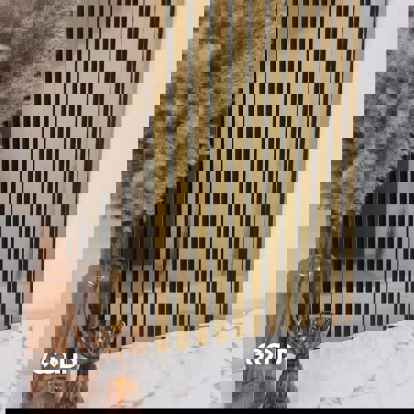 Decorative wall with gold and black slat wall panel, vase with dried plants on marble surface.