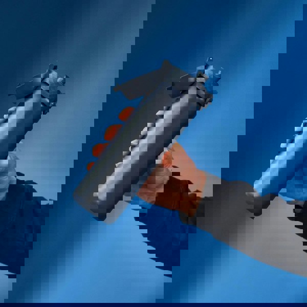 A hand holds a blue water bottle with a flip-top lid against a gradient blue background.