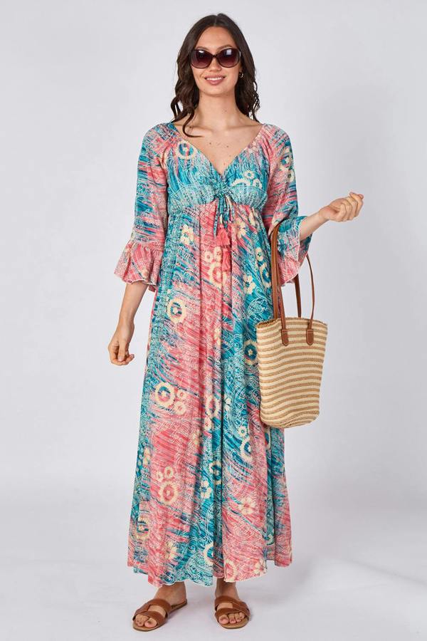 Woman wearing a colorful patterned dress holding a straw bag on a white background