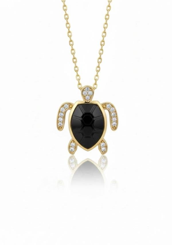 Gold turtle pendant necklace with black gemstone on a white background
