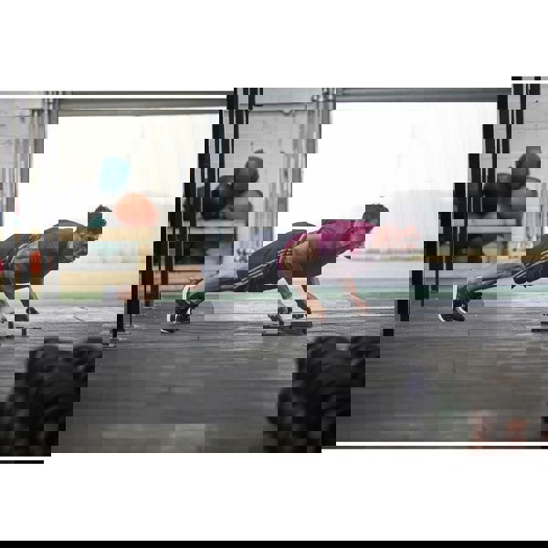 Person doing push-ups on a gym floor with fitness equipment in the background