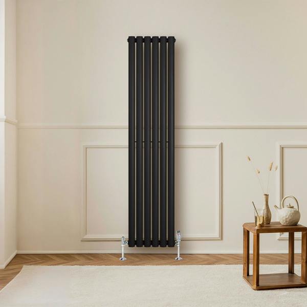 Sleek black oval single column radiator with silver valves, standing tall against a light wall, enhancing modern interior decor